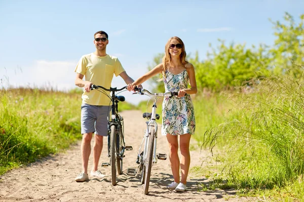 Coppia felice con biciclette su strada di campagna — Foto Stock