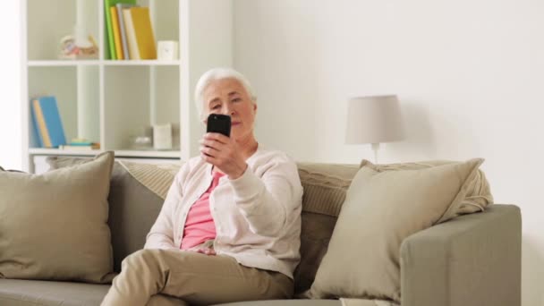 Seniorin mit Smartphone macht Selfie zu Hause — Stockvideo