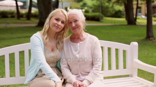 Дочь со старшей матерью сидит на скамейке в парке — стоковое видео