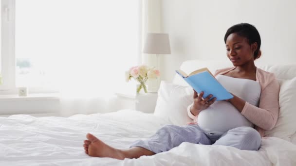 Mujer africana embarazada feliz lectura libro en casa — Vídeo de stock