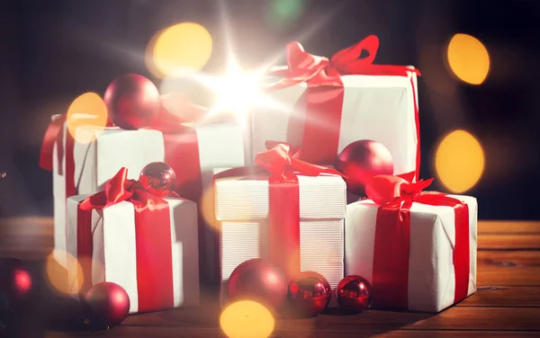 Cajas de regalo y bolas rojas de Navidad en el suelo de madera — Foto de Stock