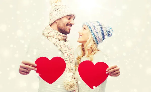 Smiling couple in winter clothes with red hearts — Stock Photo, Image