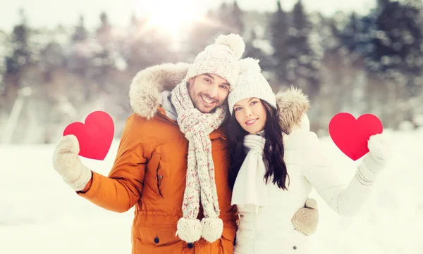 Feliz pareja con corazones rojos sobre el paisaje de invierno — Foto de Stock