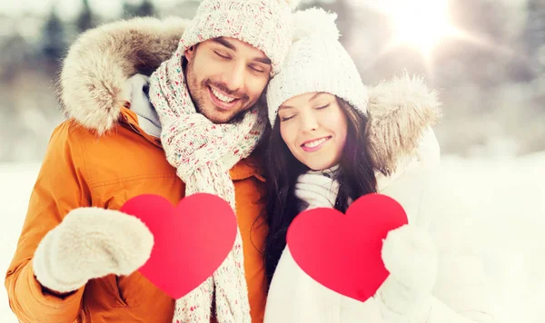 Casal feliz com corações vermelhos sobre paisagem de inverno — Fotografia de Stock