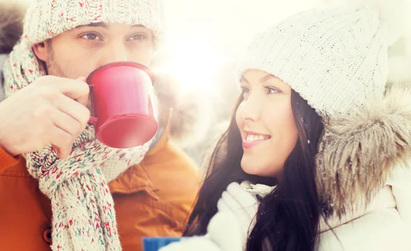 Happy couple with tea cups over winter landscape — Stock Photo, Image