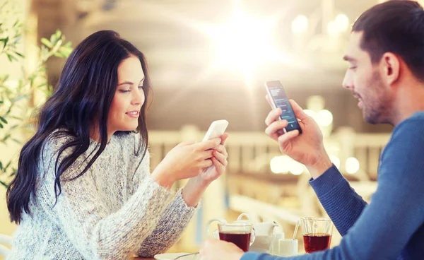 Casal feliz com smartphones bebendo chá no café — Fotografia de Stock