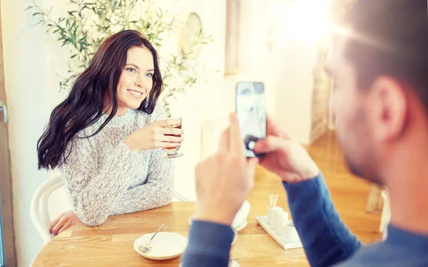 Muž fotit ženu chytrým telefonem v kavárně — Stock fotografie