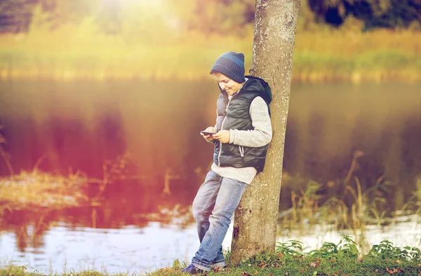 Lycklig pojke spela spelet på smartphone utomhus — Stockfoto