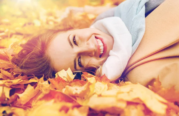 Hermosa mujer feliz acostada en hojas de otoño — Foto de Stock