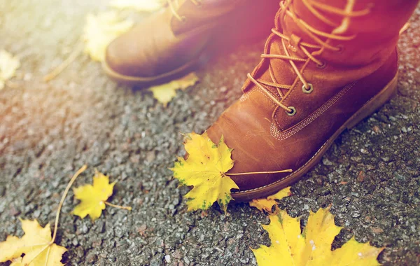 Piedi femminili in stivali e foglie autunnali — Foto Stock