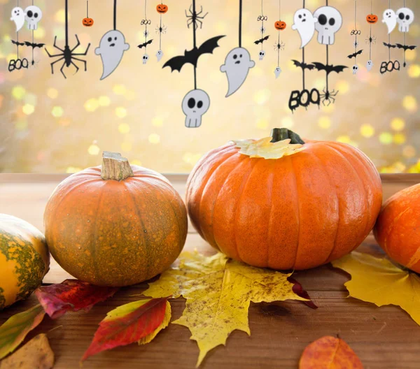 Kürbisse mit Herbstblättern und Halloween-Girlanden Stockbild