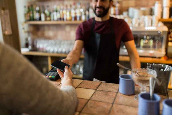 Mann mit Zahlungsterminal und Hand mit Smartphone — Stockfoto