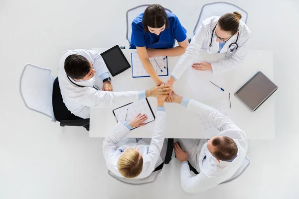Skupina lékařů, drželi se za ruce spolu u stolu — Stock fotografie