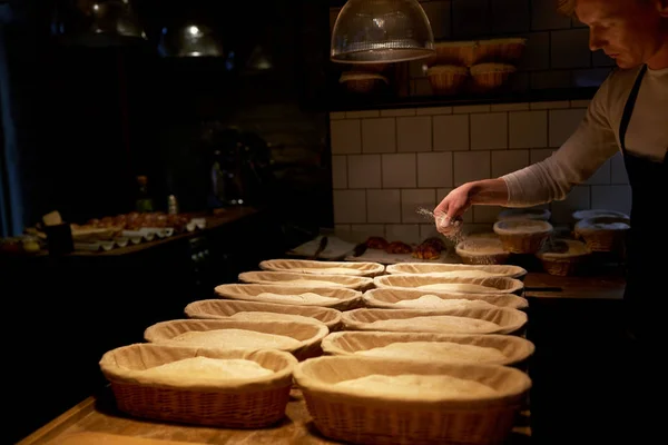 Baker with baskets for dough rising at bakery — Stock Photo, Image