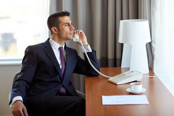 Homem de negócios chamando no telefone mesa no quarto do hotel — Fotografia de Stock