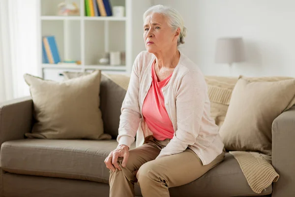 Senior woman suffering from pain in leg at home — Stock Photo, Image