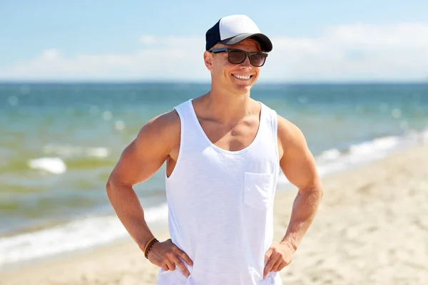 Glimlachende jonge man in een zonnebril op het zomerstrand — Stockfoto