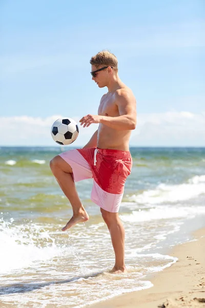 Top kumsalda futbol oynamak ile genç adam — Stok fotoğraf