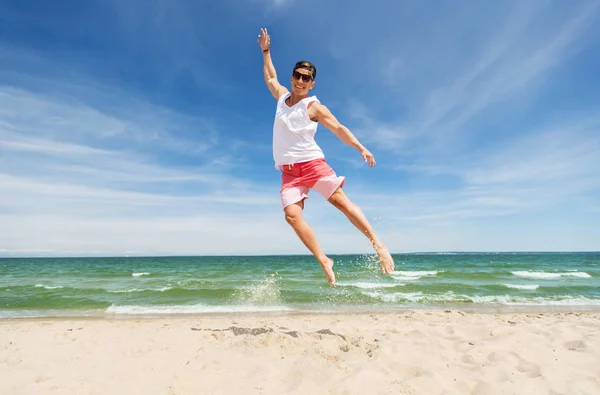 在夏天的海滩上跳跃的年轻男人微笑着 — 图库照片