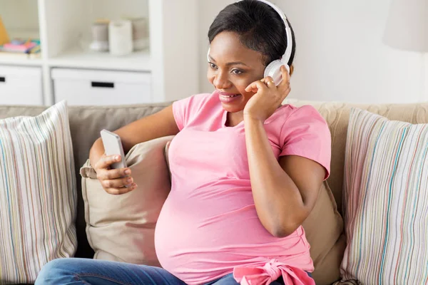 Femme enceinte dans un casque avec smartphone — Photo