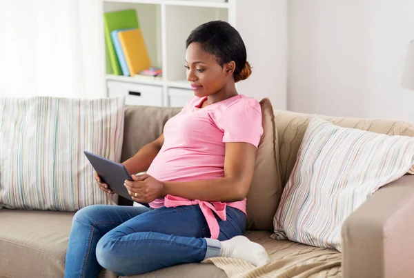 Szczęśliwa kobieta w ciąży z tabletem w domu — Zdjęcie stockowe