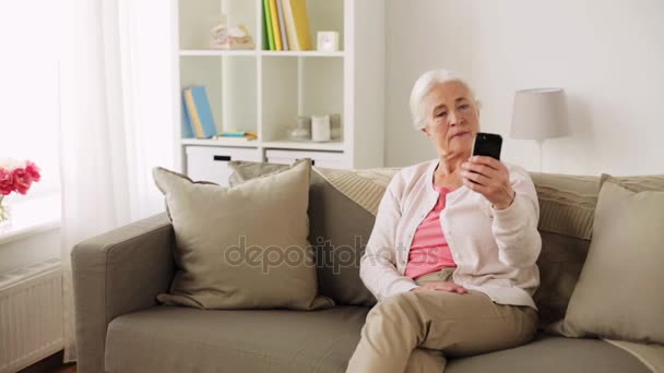 Mujer mayor con teléfono inteligente tomando selfie en casa — Vídeo de stock