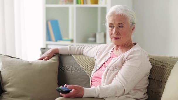 Счастливая пожилая женщина смотрит телевизор дома — стоковое видео