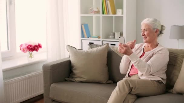 Пожилая женщина со смартфоном в видеочате — стоковое видео