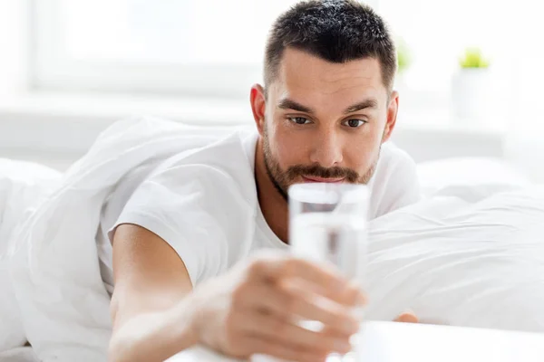 Hombre en la cama con vaso de agua en casa —  Fotos de Stock