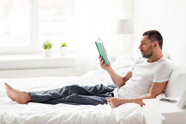 Hombre leyendo libro en la cama en casa — Foto de Stock