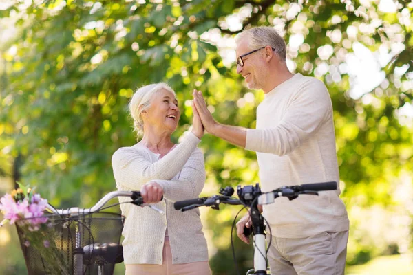 Senior paar met fietsen waardoor hoge vijf in het park — Stockfoto