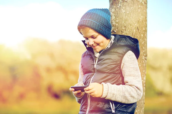 Gelukkige jongen speelspel op smartphone buitenshuis — Stockfoto