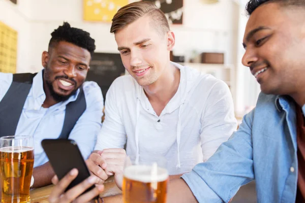 Male friends with smartphone drinking beer at bar — Stock Photo, Image