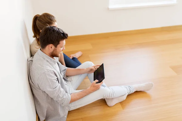 Casal feliz com computador tablet pc em nova casa — Fotografia de Stock