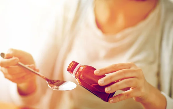 Nainen kaatamalla lääkettä pullosta lusikkaan — kuvapankkivalokuva