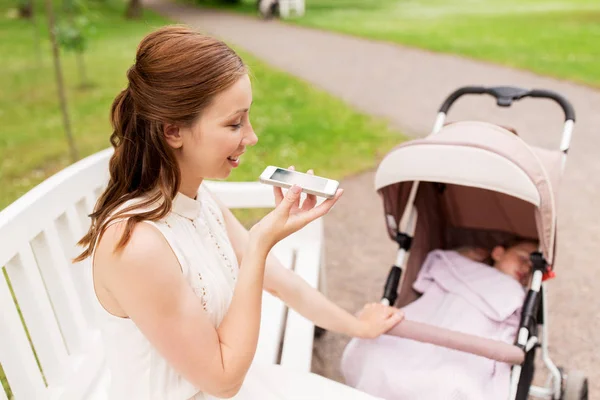 Mother with stroller and smartphone at summer park — Stock Photo, Image