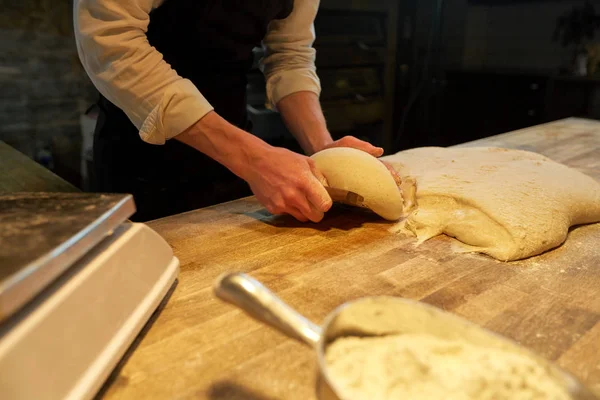 Baker portioning dough with bench cutter at bakery — Stock Photo, Image