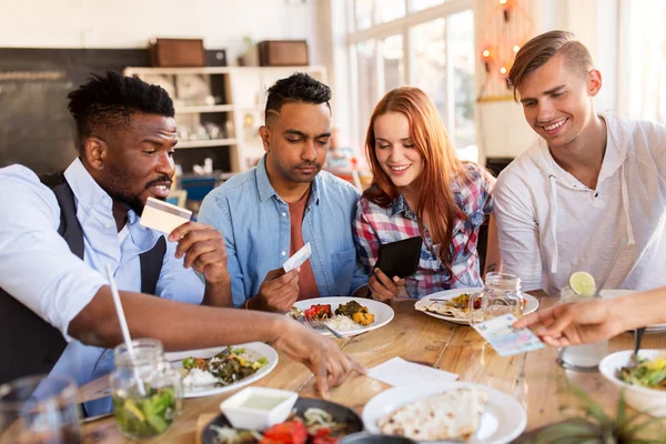 happy friends with money paying bill at restaurant