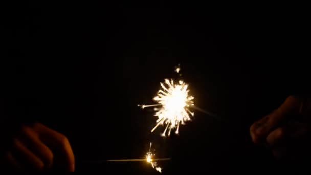 Hands playing with burning sparklers in darkness — Stock Video