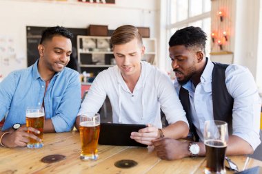 male friends with tablet pc drinking beer at bar clipart