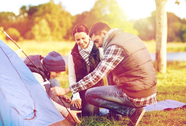 Happy family setting up tent outdoors — Stock Photo, Image