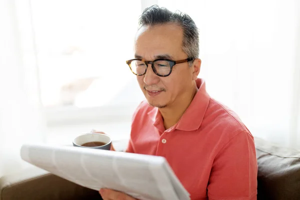 Мужчина пьет кофе и читает дома газету — стоковое фото