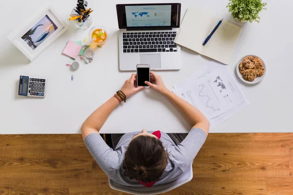 Mulher com smartphone e laptop na mesa de escritório — Fotografia de Stock