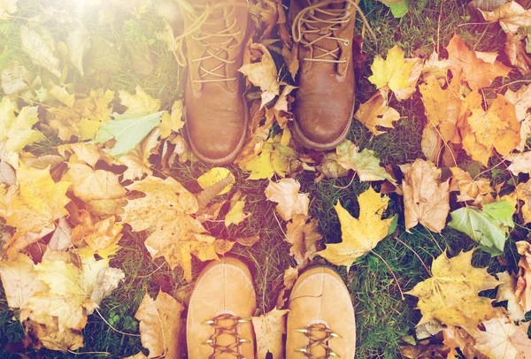 Paio di piedi in stivali e foglie di autunno — Foto Stock