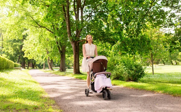 Šťastný matka s dítětem v kočárku v parku léta — Stock fotografie