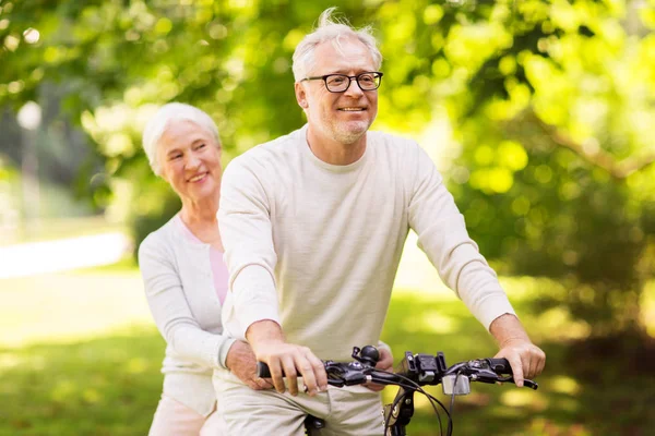 Feliz pareja de ancianos montar en bicicleta en el parque —  Fotos de Stock