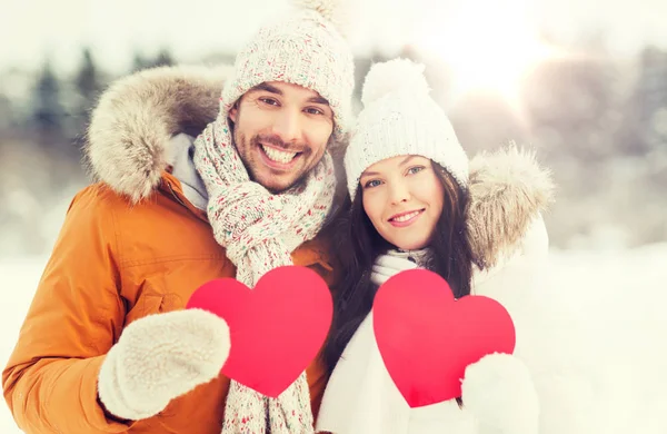 Happy couple with red hearts over winter landscape — Stock Photo, Image