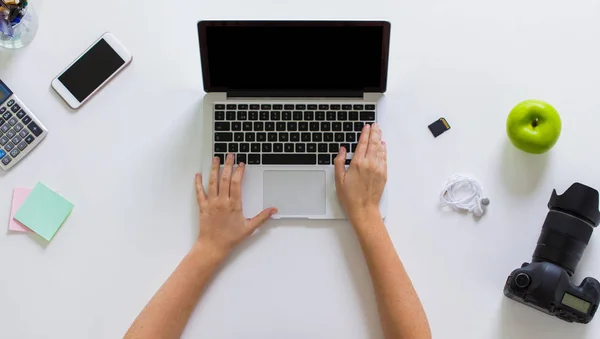 Donna con macchina fotografica che lavora su computer portatile a tavola — Foto Stock