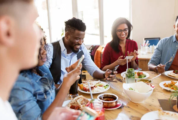 Amigos felizes com smartphones no restaurante — Fotografia de Stock