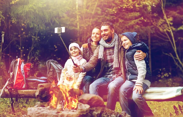 Familie met smartphone nemen selfie in de buurt van kampvuur — Stockfoto